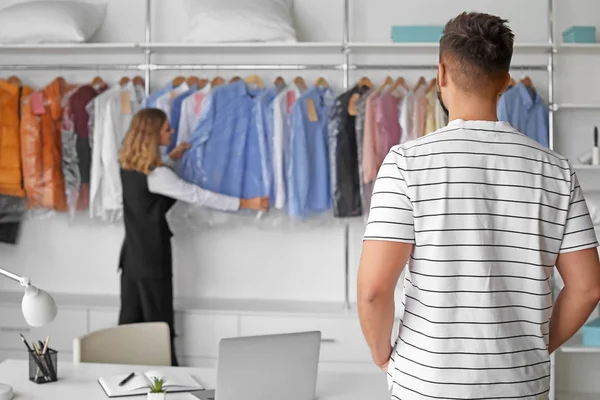 Female worker searching clean client's clothes in modern dry-cleaner's — Stock Photo, Image
