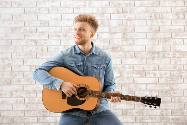 Handsome man with guitar against brick wall — Stock Photo, Image