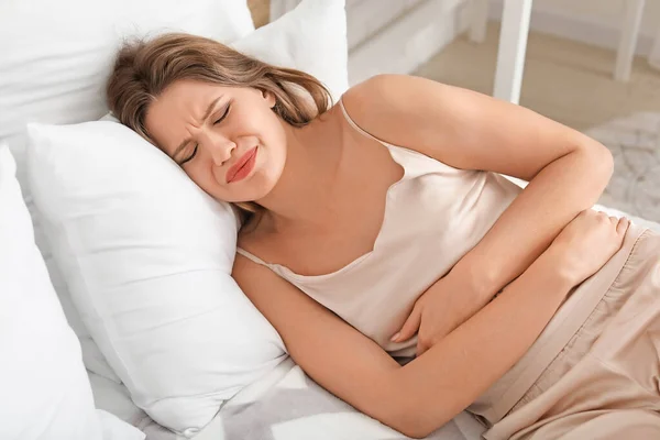 Mladá žena trpí bolestí břicha doma — Stock fotografie