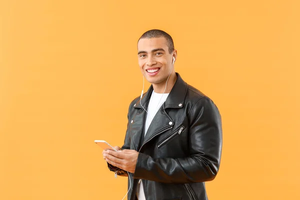 Portrait of handsome young man listening to music on color background — Stock Photo, Image