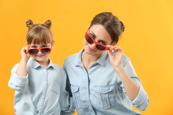 Portrait of stylish mother and daughter on color background — Stock Photo, Image