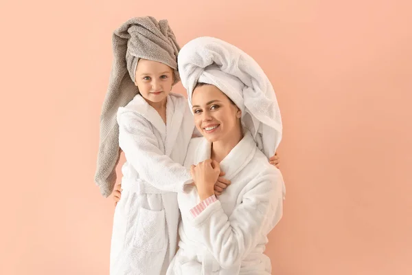 Porträt von glücklicher Mutter und Tochter in Bademänteln auf farbigem Hintergrund — Stockfoto