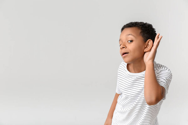 Маленький афроамериканец с проблемами со слухом на светлом фоне
