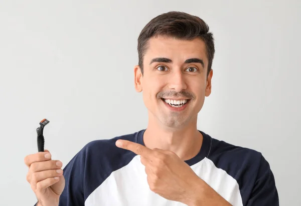 Joven guapo con navaja de afeitar sobre fondo claro — Foto de Stock