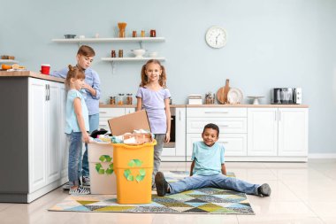 Mutfağında çöp olan küçük çocuklar ve konteynırlar. Geri dönüşüm kavramı