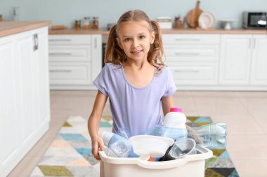 Mutfağında çöp olan küçük kız ve konteynır. Geri dönüşüm kavramı