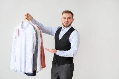 Modern kuru temizlemecinin erkek çalışanı. Arka planda kıyafetleri var.