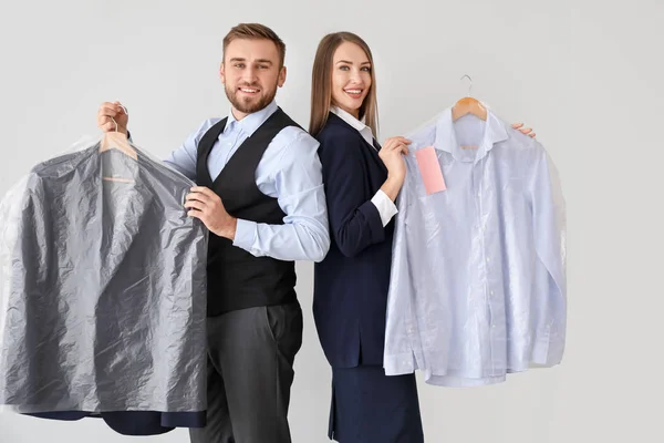 Trabajadores de la moderna tintorería con ropa sobre fondo claro — Foto de Stock