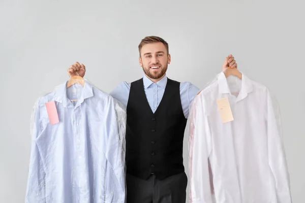 Mannelijke werknemer van moderne stomerij met kleding op lichte achtergrond — Stockfoto