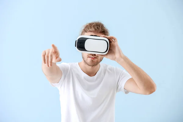 Young man with VR glasses on color background — Stock Photo, Image