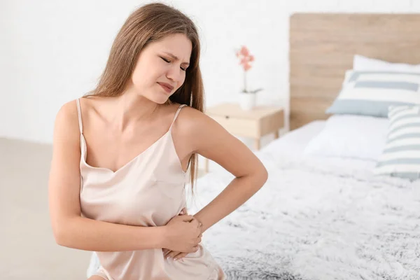 Young woman suffering from back pain in bedroom — Stock Photo, Image