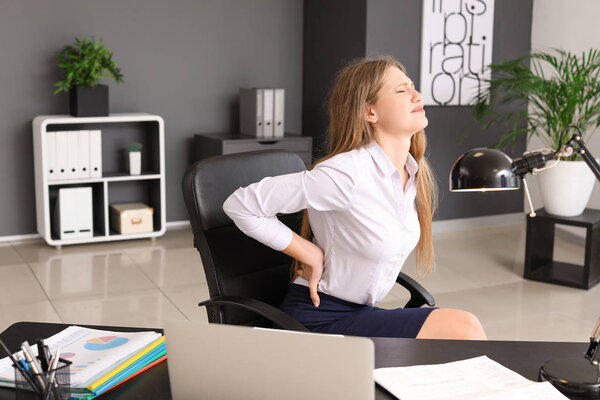 Young businesswoman suffering from back pain in office