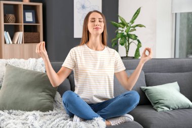 Evinde meditasyon yapan güzel genç bir kadın.