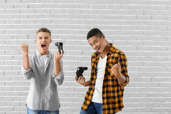 Εφηβικά αγόρια που παίζουν βιντεοπαιχνίδια με φόντο γκρι τούβλο — Φωτογραφία Αρχείου