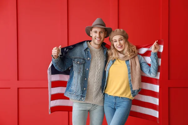 Casal jovem com bandeira dos EUA em fundo de cor. Celebração do Dia Memorial — Fotografia de Stock