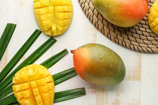 Sweet ripe mangoes on light wooden table — Stock Photo, Image