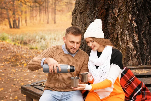 Loving young couple drinking hot tea in autumn park — Stock Photo, Image