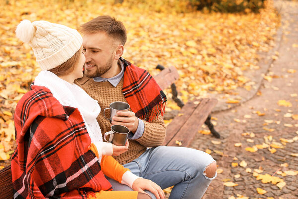 Loving young couple drinking hot tea in autumn park