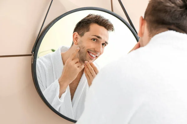 Handsome man shaving near mirror in bathroom — Stock Photo, Image