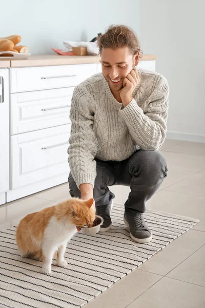 Man feeding cute cat in kitchen — Stock Photo, Image