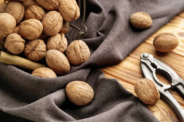 Корзина с вкусными грецкими орехами и орехами на деревянном столе — стоковое фото