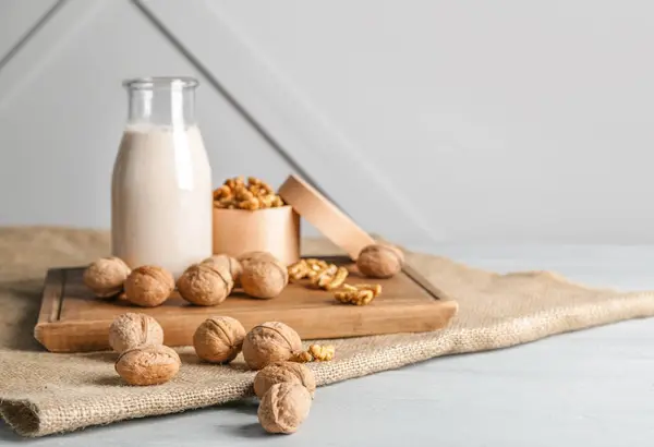 Láhev mléka s chutnými vlašskými ořechy na stole — Stock fotografie