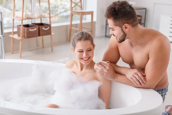 Young man helping his wife to take bath — Stock Photo, Image