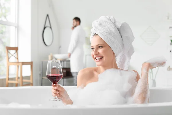 Mulher bonita bebendo vinho enquanto toma banho — Fotografia de Stock