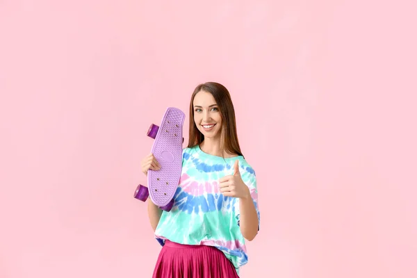 Красивая молодая женщина со скейтбордом на цветном фоне — стоковое фото