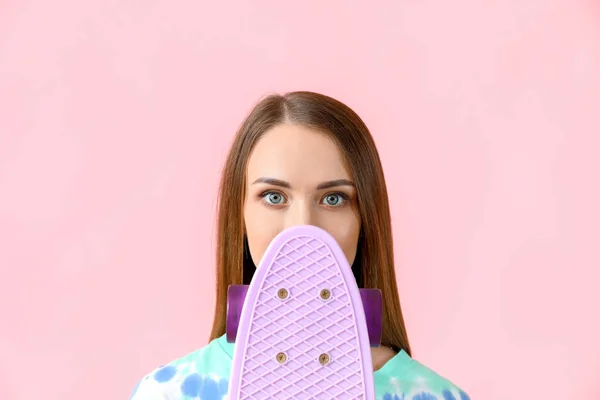 Beautiful young woman with skateboard on color background — Stock Photo, Image