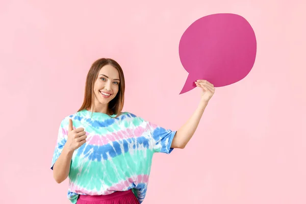 Beautiful young woman with blank speech bubble showing thumb-up on color background — Stock Photo, Image