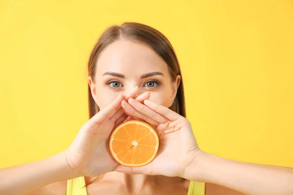 Beautiful young woman with orange on color background — Stock Photo, Image