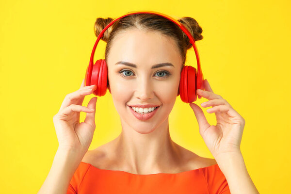 Beautiful young woman listening to music on color background