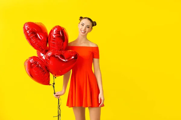 Beautiful young woman with heart-shaped balloons on color background — Stock Photo, Image