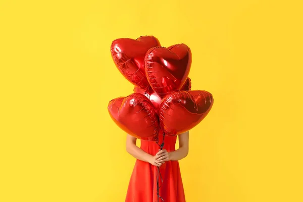 Belle jeune femme avec des ballons en forme de coeur sur fond de couleur — Photo