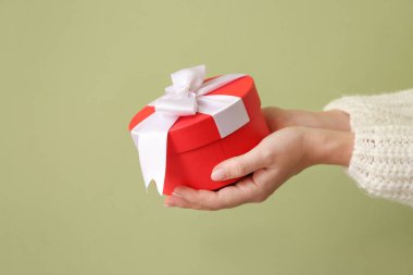 Renkli arka planda Sevgililer Günü hediyesi olan kadın elleri