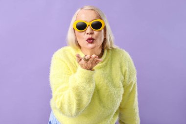 Renkli arka planda öpücük üfleme moda olgun kadın