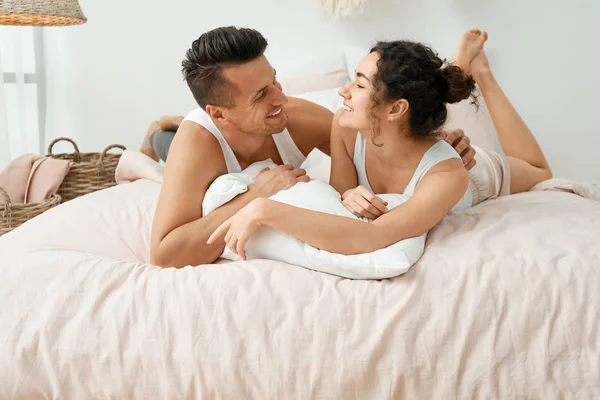 Happy young couple lying on bed at home — Stock Photo, Image