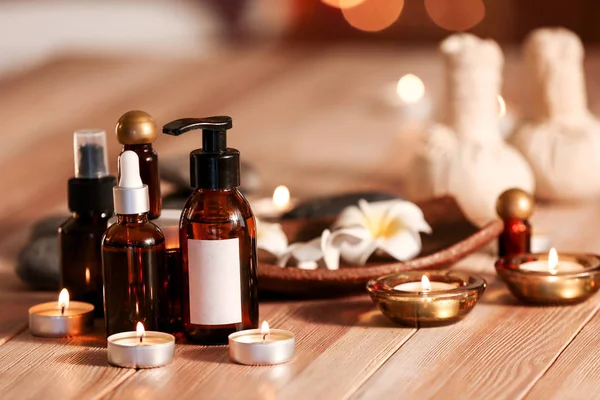 Bottles of essential oil and candles on table in spa salon — Stock Photo, Image
