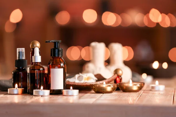 Bottles of essential oil and candles on table in spa salon — Stock Photo, Image