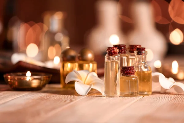Garrafas de óleo essencial e flores na mesa no salão de spa — Fotografia de Stock