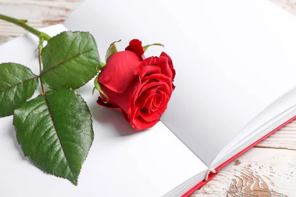 Hermosa rosa y cuaderno en blanco sobre fondo de madera, primer plano. Celebración de San Valentín — Foto de Stock