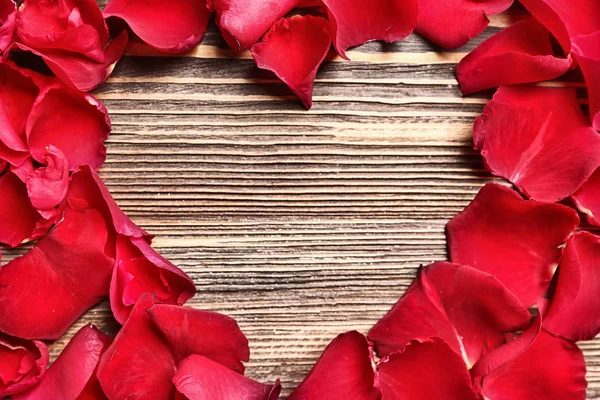 Ahşap arka planda gül yapraklarından yapılmış bir kalp. Sevgililer Günü kutlaması — Stok fotoğraf