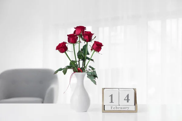 Calendar with date of Valentine's Day and roses on table in room — Stock Photo, Image