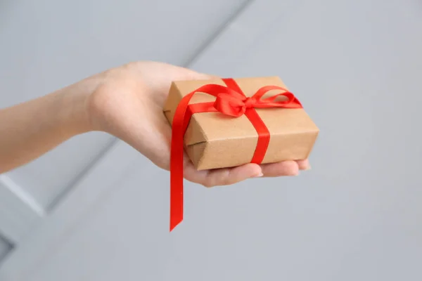 Female hand with gift for Valentine's Day on grey background — Stock Photo, Image