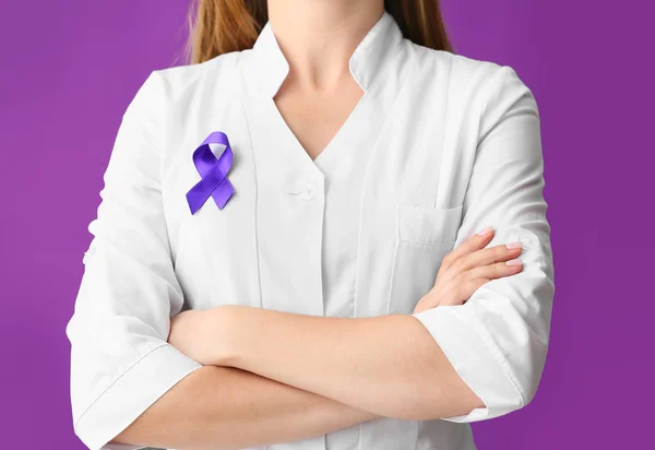 Médico con cinta púrpura como símbolo del Día Mundial del Cáncer sobre fondo de color — Foto de Stock