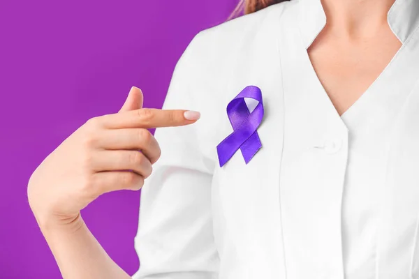 Médico con cinta púrpura como símbolo del Día Mundial del Cáncer sobre fondo de color, primer plano — Foto de Stock