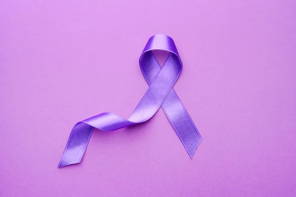 Cinta púrpura como símbolo del Día Mundial del Cáncer sobre fondo de color — Foto de Stock