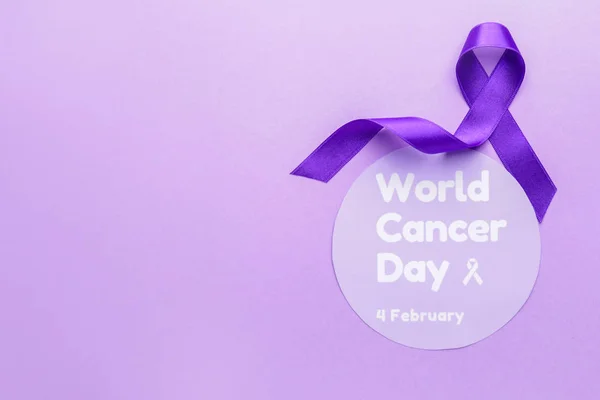 文字付きの紙世界がんの日と色の背景に紫色のリボン — ストック写真