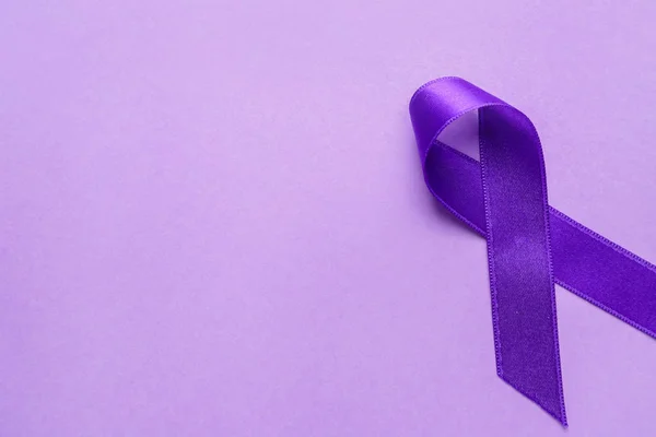 Purple ribbon as symbol of World Cancer Day on color background — Stock Photo, Image